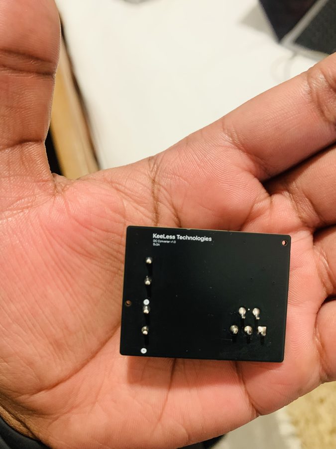 DC Converter v1.0 held in a palm, silkscreen side up, reading KeeLess Technologies, DC Converter v1.0, 5V 3A